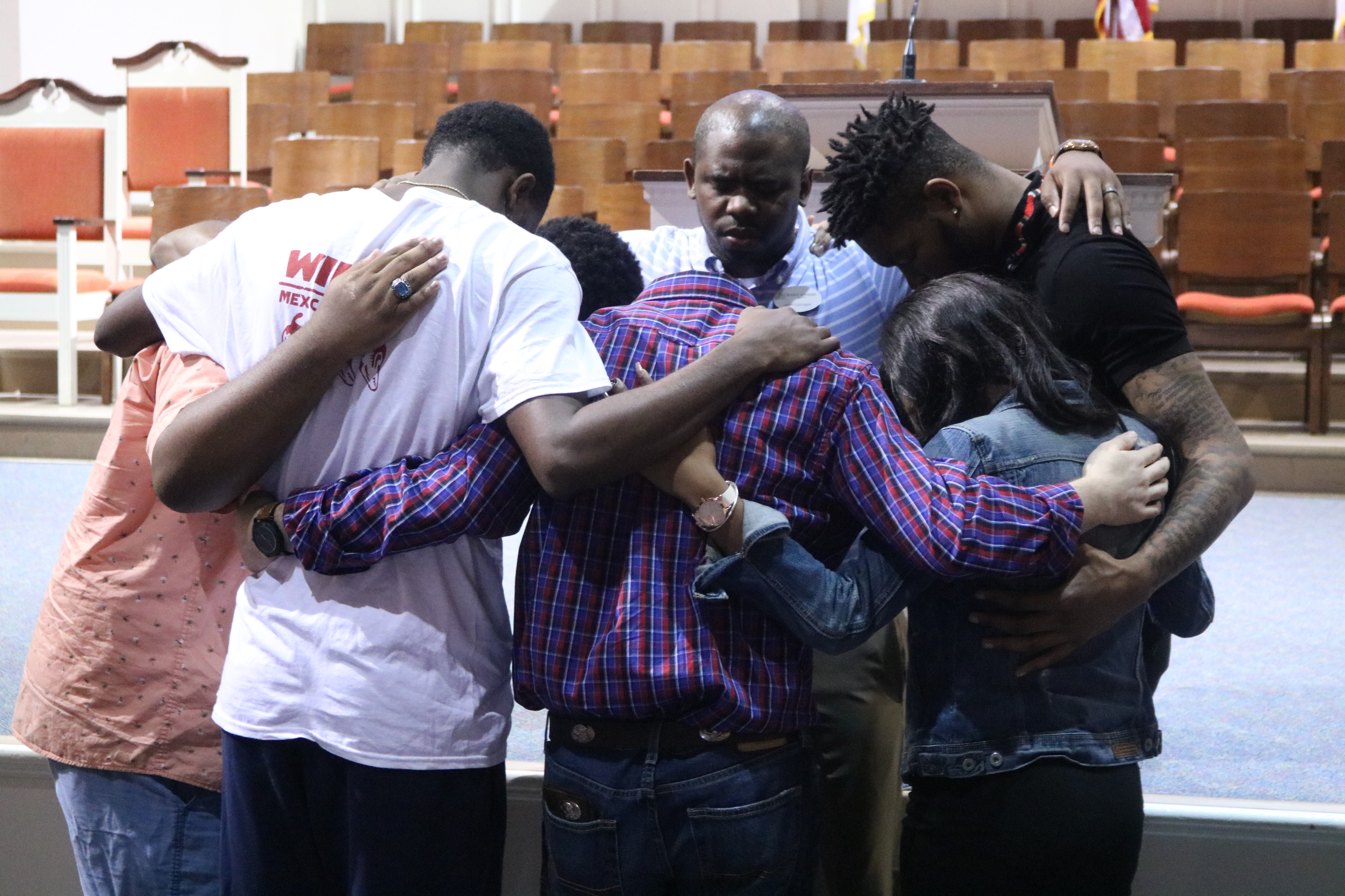 Campus Pastor Steve Edwards, center, prays with a group of students during the February 20 chapel service. Edwards acted as the speaker for the service. Photo Credit: Jose Carrillo-Garcia